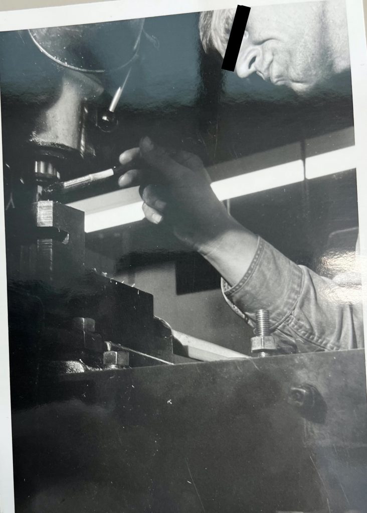 Man applying oil to parts of a drill press machine