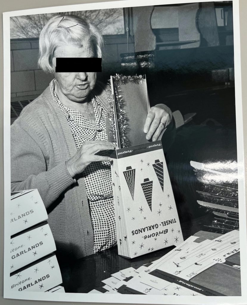 Resident standing before a large pile of coil bodies, holding a pair of pliers