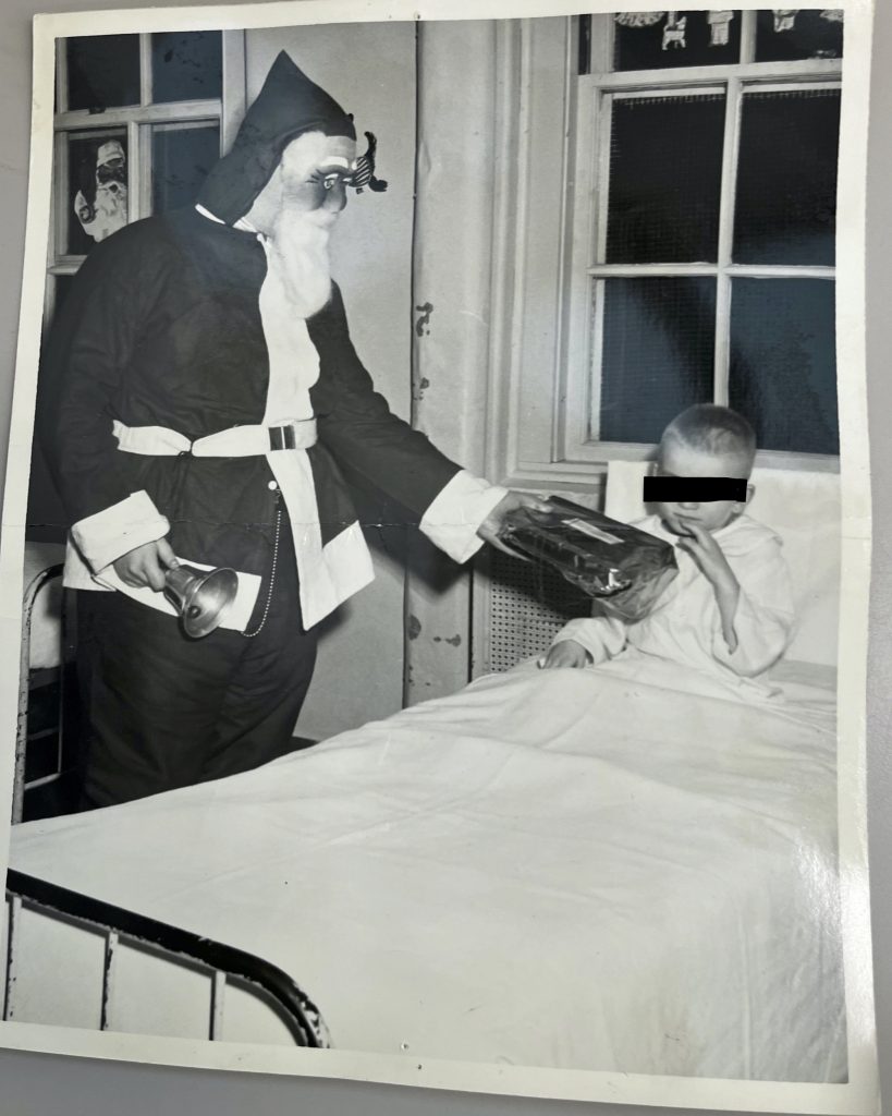 Man dressed as Santa Claus wearing a plastic mask