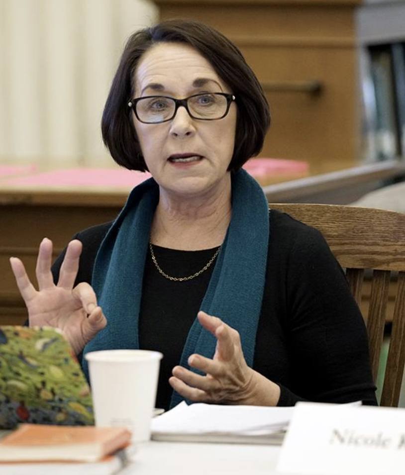 Brenda Brueggemann speaking at a conference, gesturing while addressing the audience