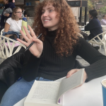 Jess Gallagher, reading a book at a coffee shop