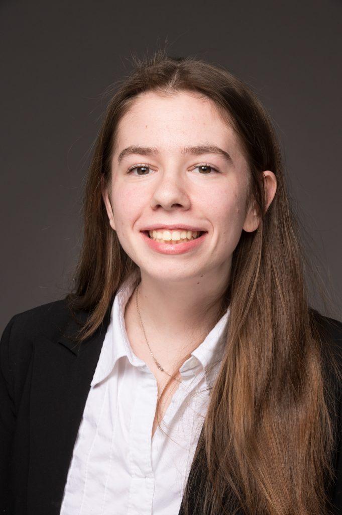 Portrait of Madison Bigelow, smiling with brown hair and a collared shirt