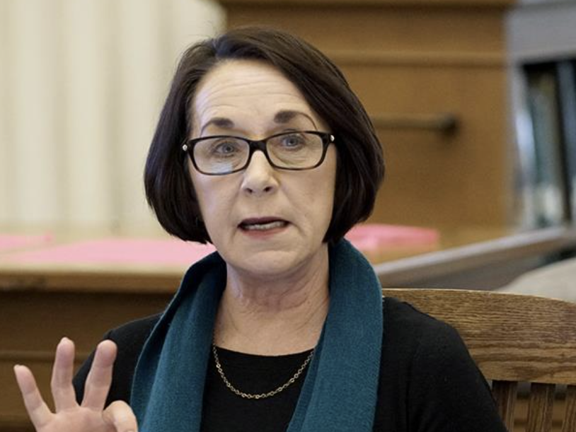 Brenda Brueggemann speaking at a conference, gesturing while addressing the audience