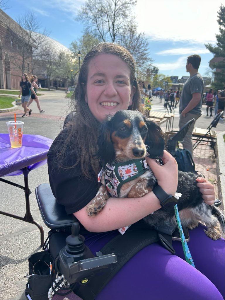 Portrait of Gabby DiSalvo holding a small dog in her arms, smiling at the camera